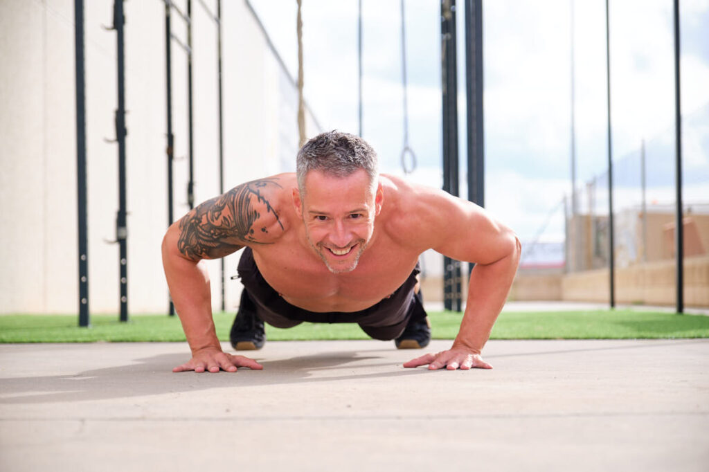 Hombre entrenando flexiones al aire libre en un box de crossfit, ejemplo de marketing digital fitness y estilo de vida deportivo.